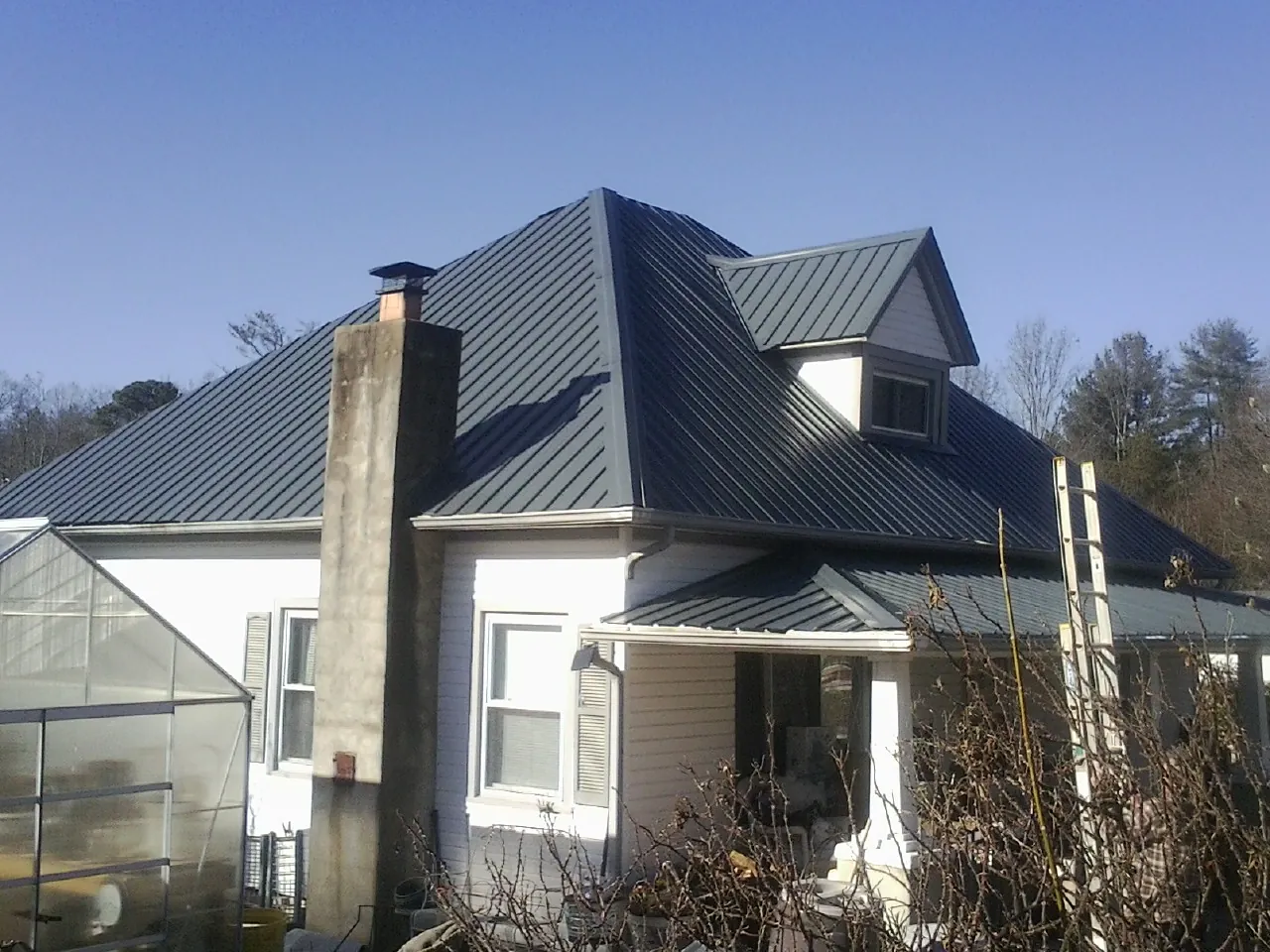 Dark blue standing seam metal roof on a white farmhouse with dormer — Slate & Tile Roof Repair by Roofing Brothers in Kittanning