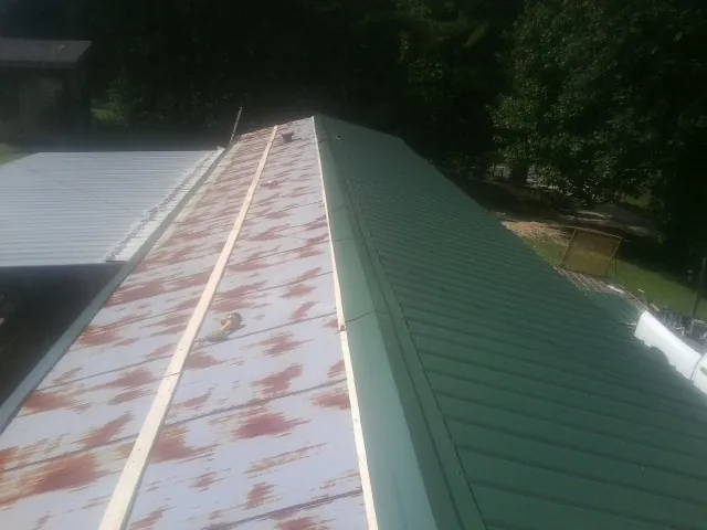 Old rusted panels beside newly installed green metal roofing — Wind Damage Roof Repair by Roofing Brothers in Kittanning