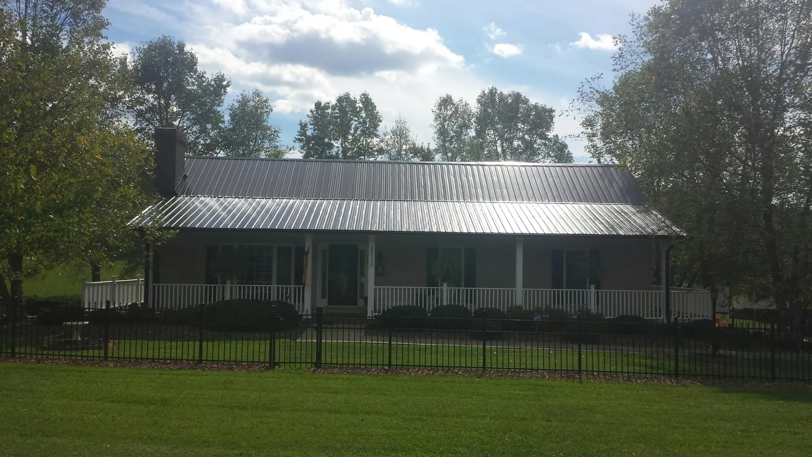 Gray metal roof on a brick ranch with a full width front porch — Gutter Guard Installation work by our crew in Kittanning