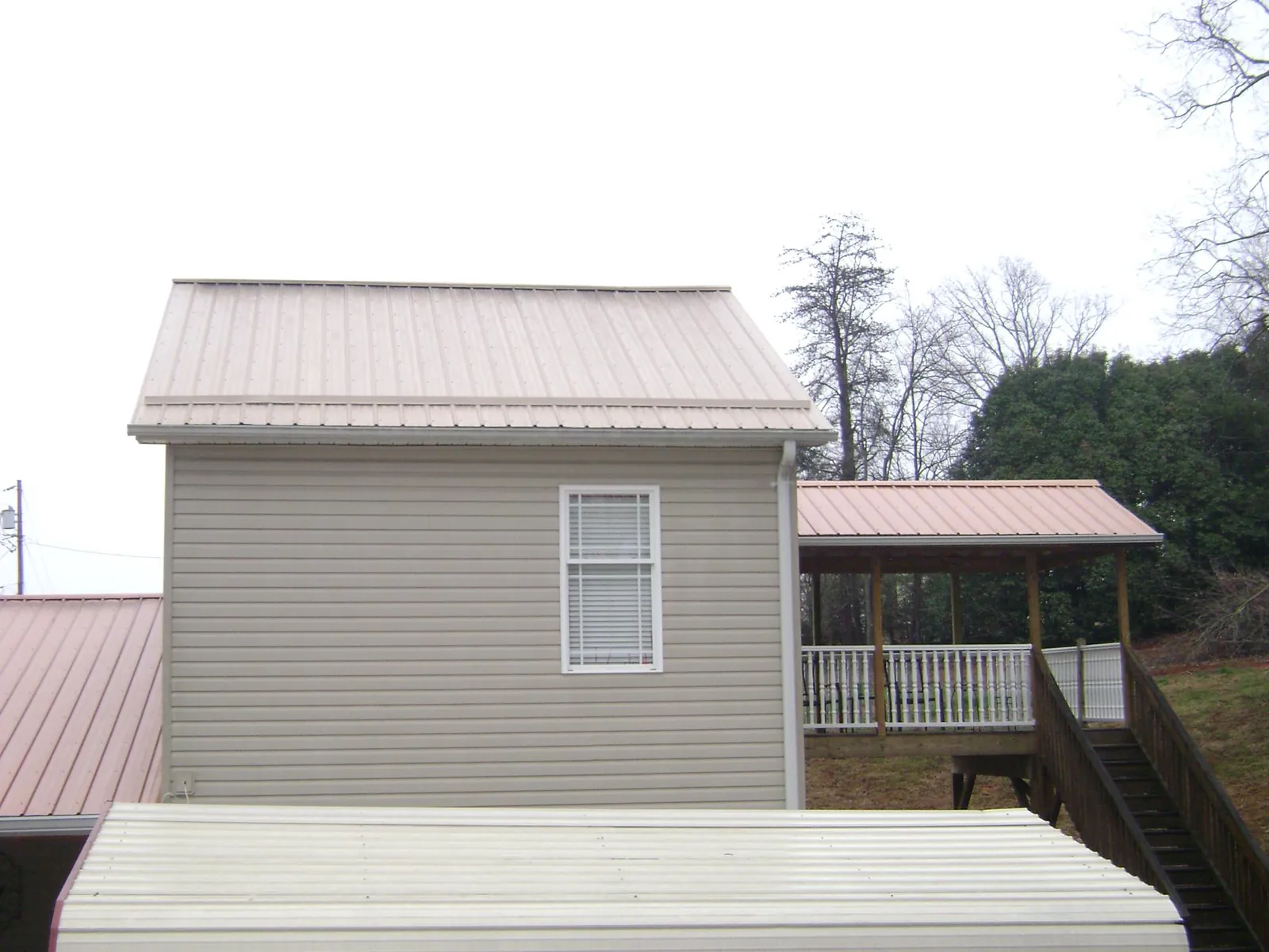 Tan metal roofs on a two story addition and attached porch, from a Roof Replacement job in Kittanning