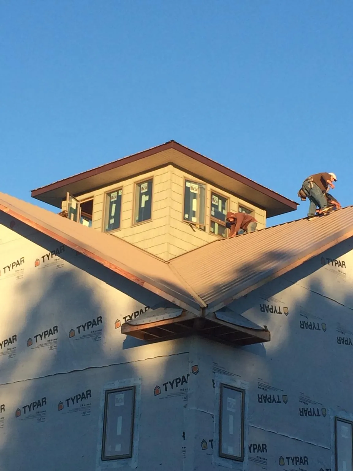 Roofers working around a rooftop cupola on a new metal roof at sunset — Roof Waterproofing in Kittanning by Roofing Brothers